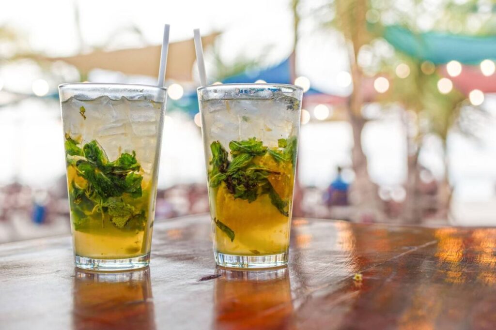 Two refreshing cocktails with mint and ice on a wooden bar overlooking the beach in St Maarten