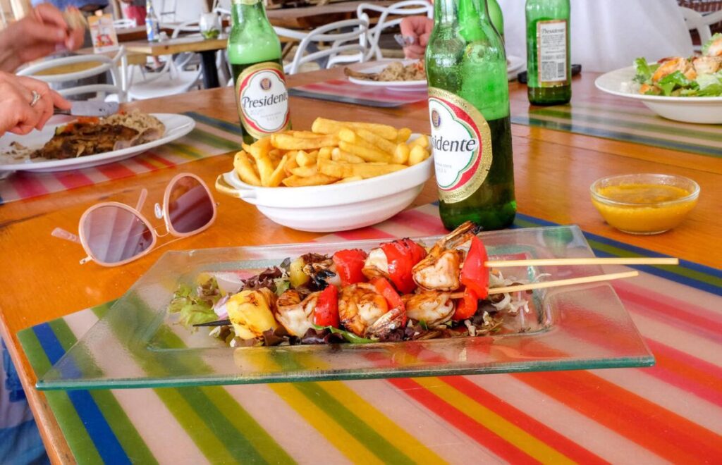 Plate of grilled shrimp skewers with fries and cold beers at a casual restaurant on the St Maarten Boardwalk